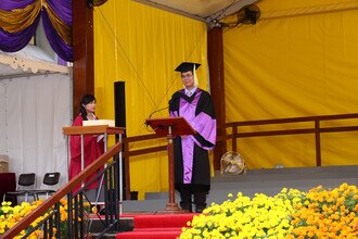 Procession member proudly presenting the graduates on stage