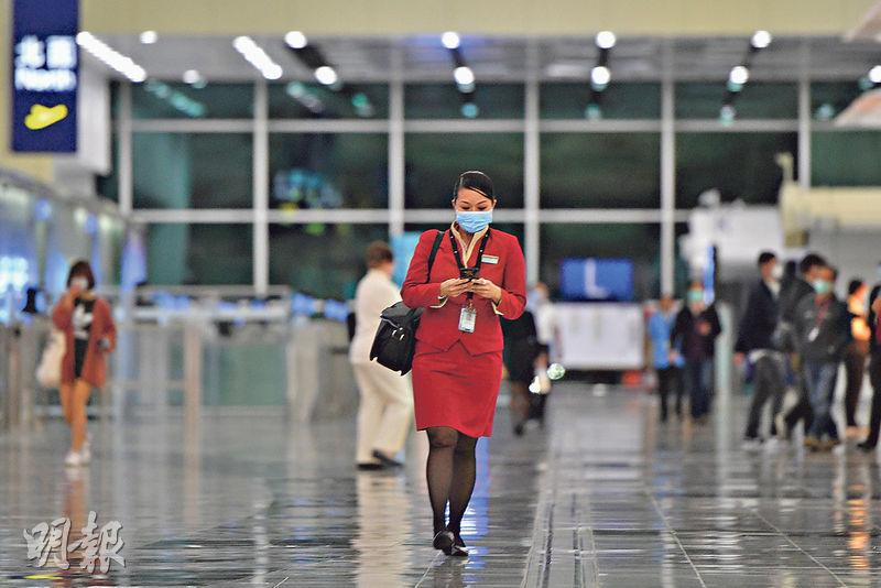 國泰有空姐確診新型冠狀病毒,為本港首宗同類個案。圖為一國泰空姐(紅衣者)在香港機場離境大堂戴着口罩。 (鄧宗弘攝)