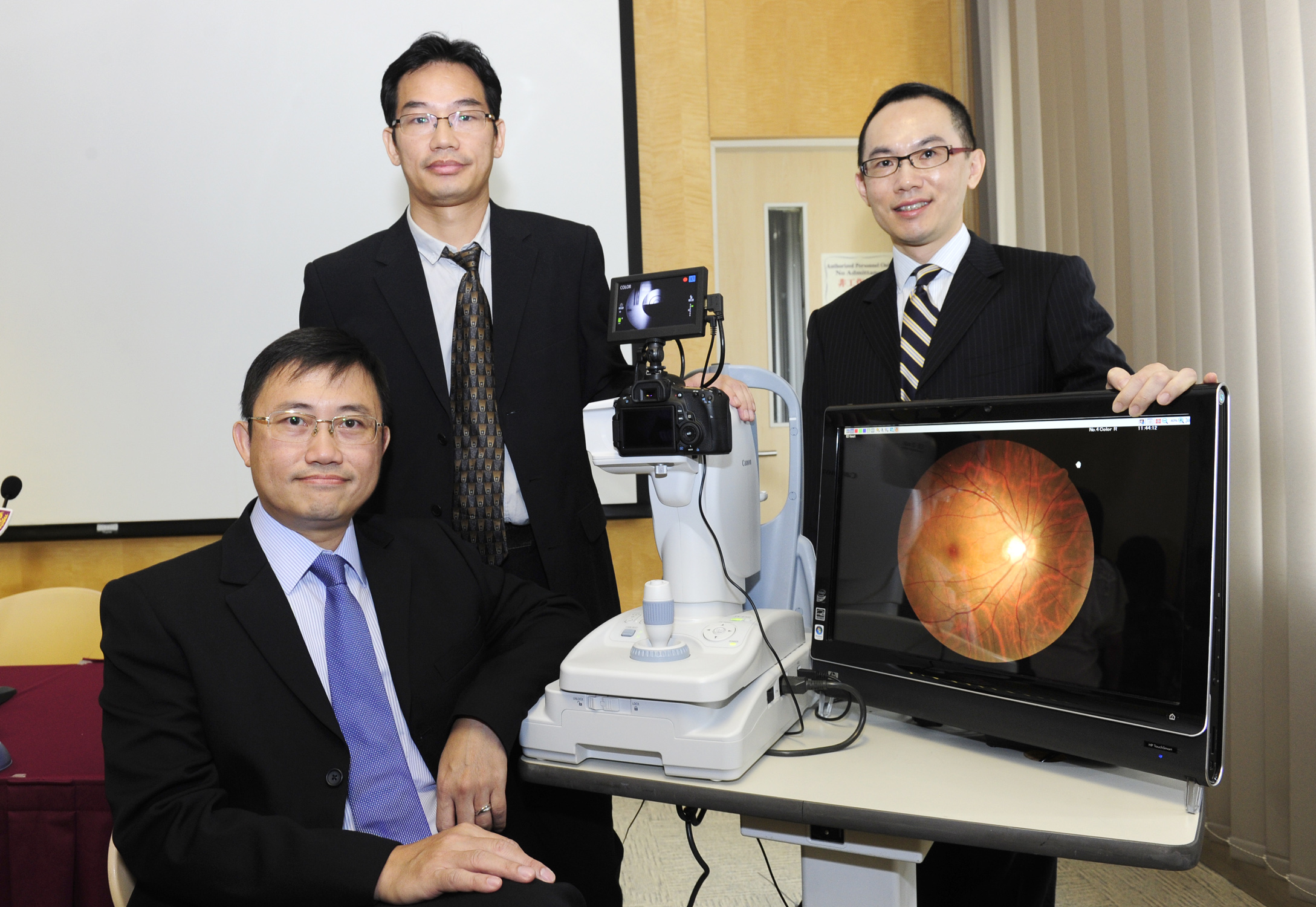 From left: Prof. Benny Chung Ying ZEE, Head of Division, Division of Biostatistics, The Jockey Club School of Public Health and Primary Care; Dr Jack Jock Wai LEE, Biostatistician, Division of Biostatistics, The Jockey Club School of Public Health and Primary Care; and Prof. Vincent Chung Tong MOK, Professor, Division of Neurology, Department of Medicine and Therapeutics at CUHK show the fundus camera and a computer with an automatic retinal image analysis system.