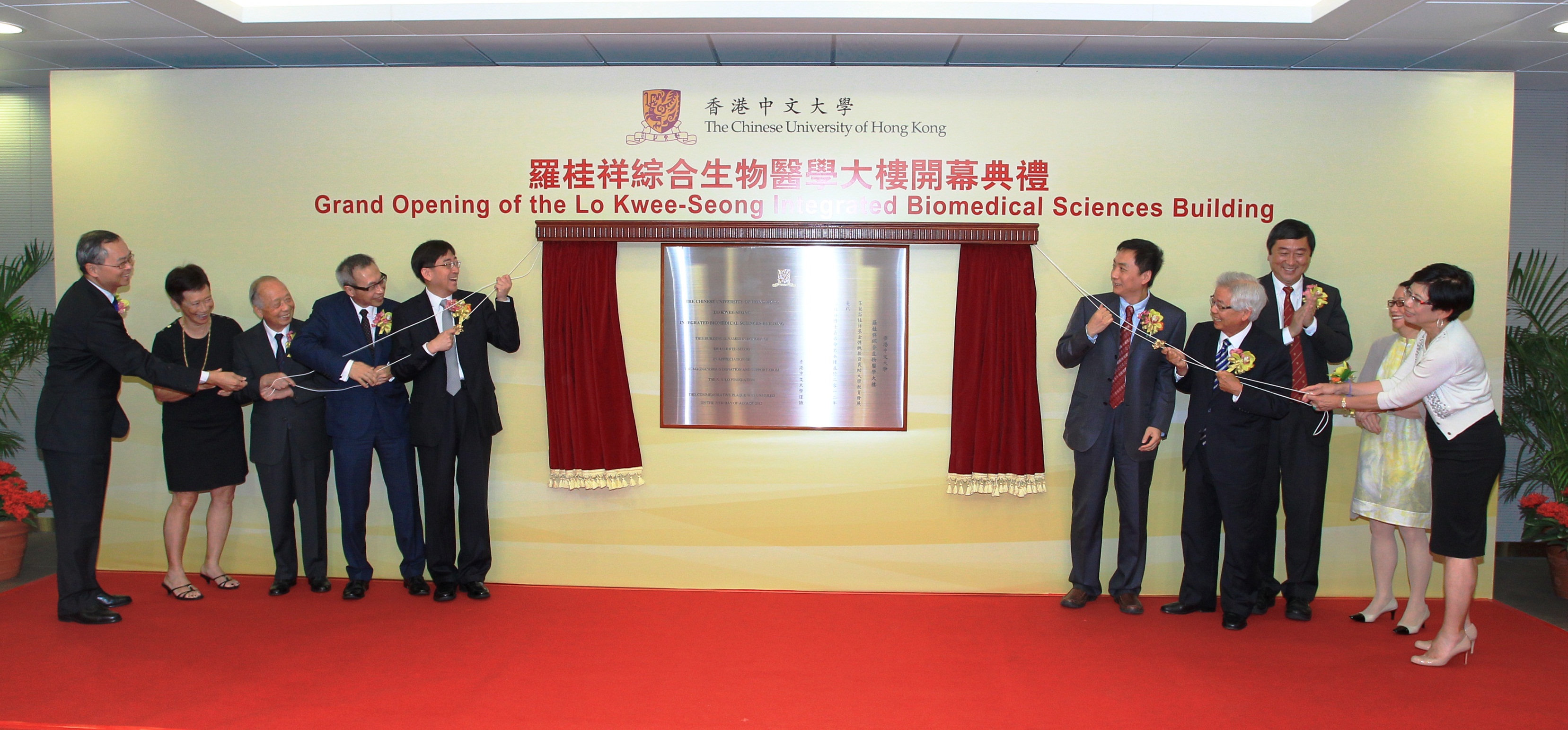 Officiating guests unveil the plaque of the building: (from left) Professor Fok Tai-fai, Dean of Medicine, CUHK; Mrs. Chan Lo Mo-lin, Irene, Trustee, K. S. Lo Foundation; Mr. Lo Kai-tun, Trustee, K. S. Lo Foundation; Dr. Lo Tak-shing, Peter, Chairman, K. S. Lo Foundation; Dr. the Honorable Ko Wing-man, Secretary for Food and Health, Hong Kong Special Administrative Region; Mr. Wang Zhutian, Assistant Director, China National Center for Food Safety Risk Assessment; Mr. Lo Yau-lai, Winston, Executive Chairman, Vitasoy International Holdings Ltd.; Professor Joseph J. Y. Sung, Vice-Chancellor and President, CUHK; Ms. Lo Mo-ching, Myrna, Trustee, K. S. Lo Foundation; and Ms. Lo Mo-ling, Yvonne, Trustee, K. S. Lo Foundation