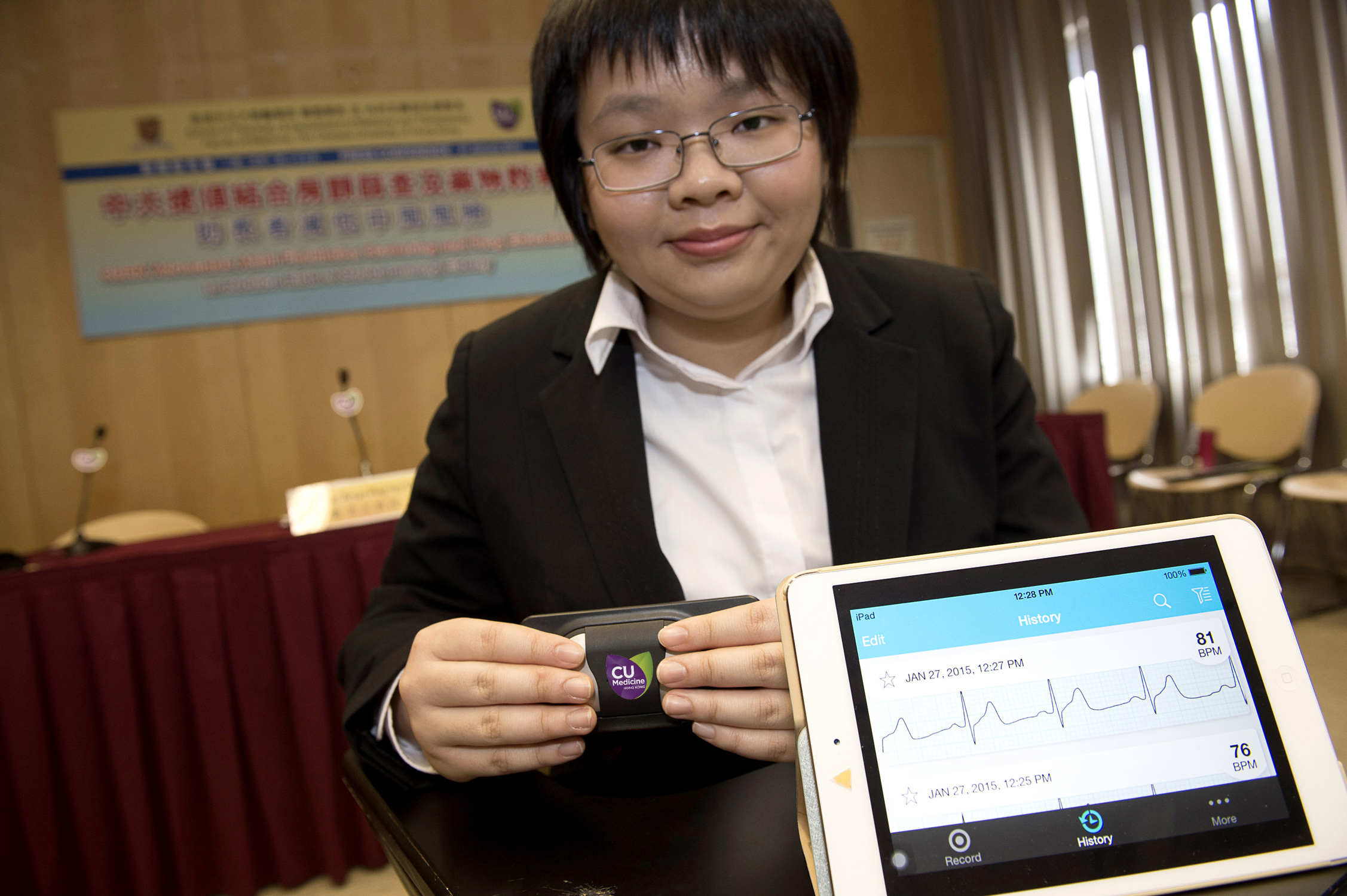 学生义工示范使用手提心电图检测器进行房颤检查。